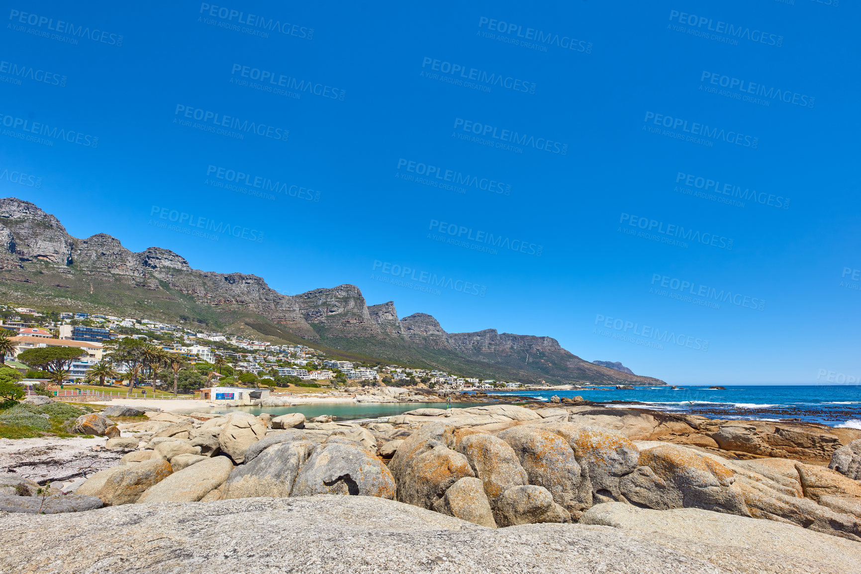 Buy stock photo Landscape of a summer holiday destination with a unique mountain range near a rocky beach in South Africa. View of the twelve apostles in Cape Town and a calm ocean against a bright blue horizon.