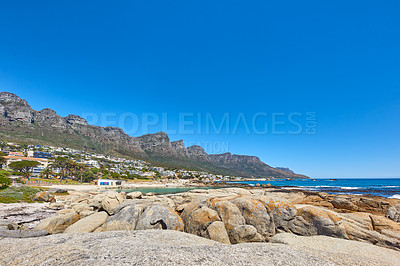 Buy stock photo Landscape of a summer holiday destination with a unique mountain range near a rocky beach in South Africa. View of the twelve apostles in Cape Town and a calm ocean against a bright blue horizon.