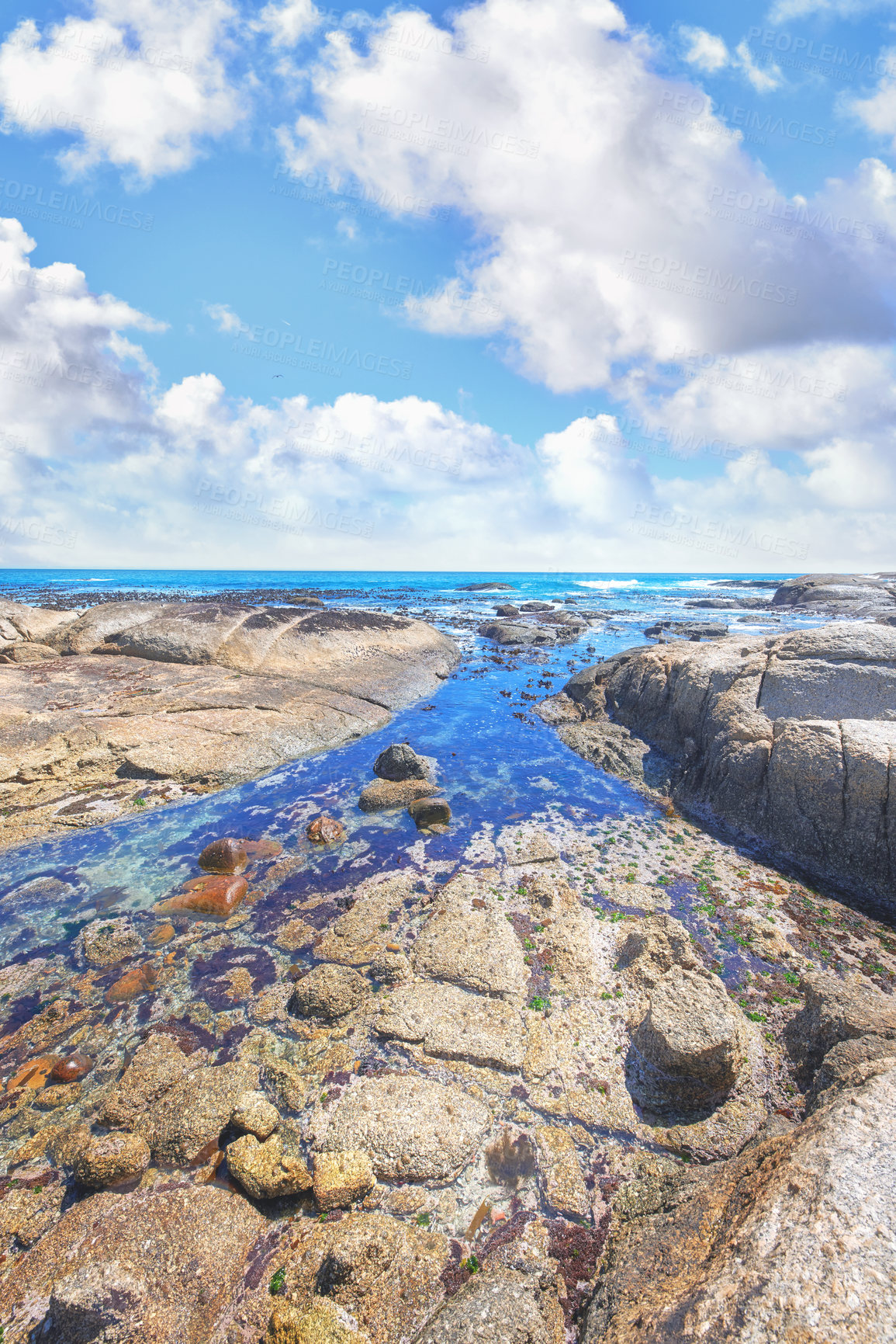 Buy stock photo Ocean view on a shallow rocky shoreline with Lion's Head, Table Mountain National Park in Cape Town, South Africa in the background. Quiet calm beach during sunset on a beautiful summer day