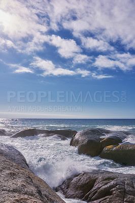 Buy stock photo Rocks in the ocean under a blue cloudy sky with copy space. Scenic landscape of beach waves splashing against boulders or big stones in the sea at a popular summer location in Cape Town, South Africa