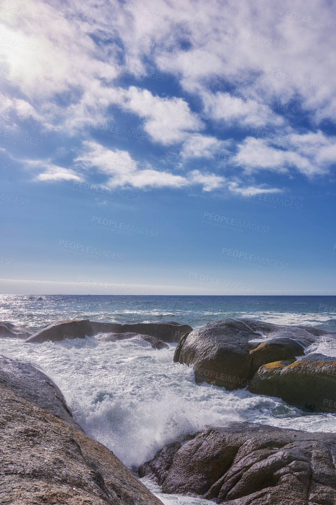 Buy stock photo Rocks in the ocean under a blue cloudy sky with copy space. Scenic landscape of beach waves splashing against boulders or big stones in the sea at a popular summer location in Cape Town, South Africa