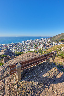 Buy stock photo Bench near a cliff on the mountains overlooking the ocean on a blue sky with copy space. Landscape of an outdoor seat area on a mountaintop with breathtaking view of nature in Cape Town, South Africa