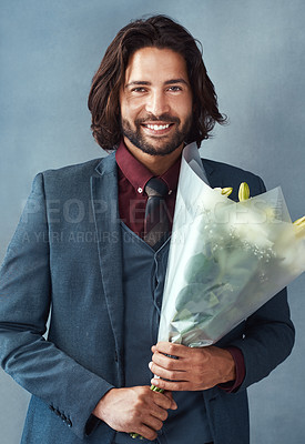 Buy stock photo Studio shot of a stylishly dressed handsome young man holding a bouquet of flowers against a gray background