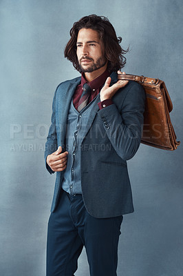 Buy stock photo Studio shot of a handsome and dapper young man carrying a bag against a grey background