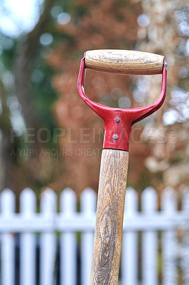 Buy stock photo Closeup of a shovel handle in a garden outside against a blur background. Red gardening tool or equipment used in a backyard, park or farm land for shoveling, planting and basic outdoor maintenance