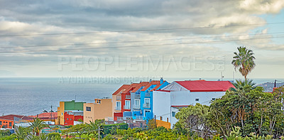 Buy stock photo Scenic view of vibrant colour houses, sea and blue sky with clouds and copy space in Santa Cruz de La Palma in Spain. Tropical palm trees growing by infrustructure buildings in tourism destination