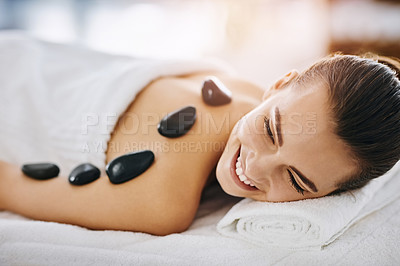 Buy stock photo Hot stone massage, smile and woman in spa, on bed or table for luxury treatment or wellness. Happy, relax and rock on back of happy customer in health resort for alternative therapy or healing