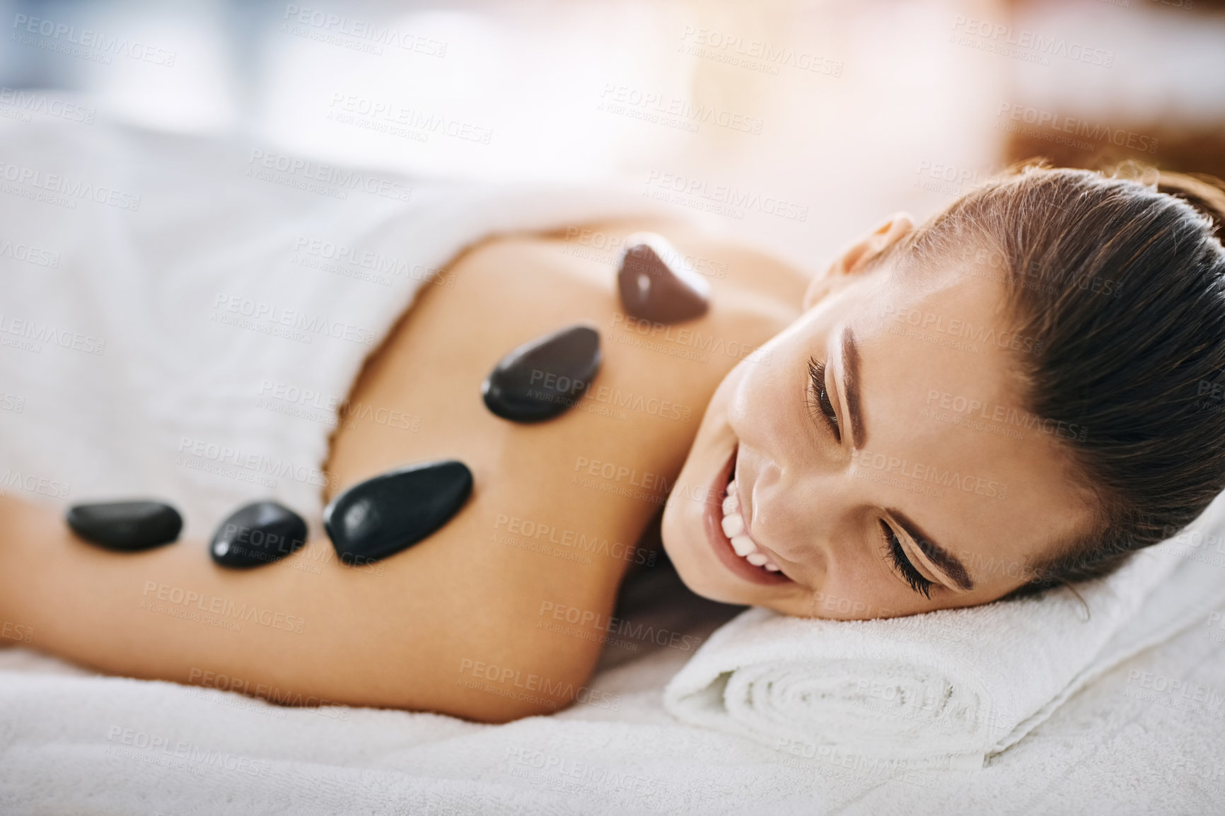Buy stock photo Shot of a young woman getting hot stone therapy at a spa