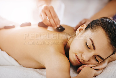 Buy stock photo Shot of a young woman getting hot stone therapy at a spa