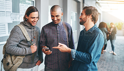Buy stock photo Shot of a group of young students using a smartphone together outdoors on campus
