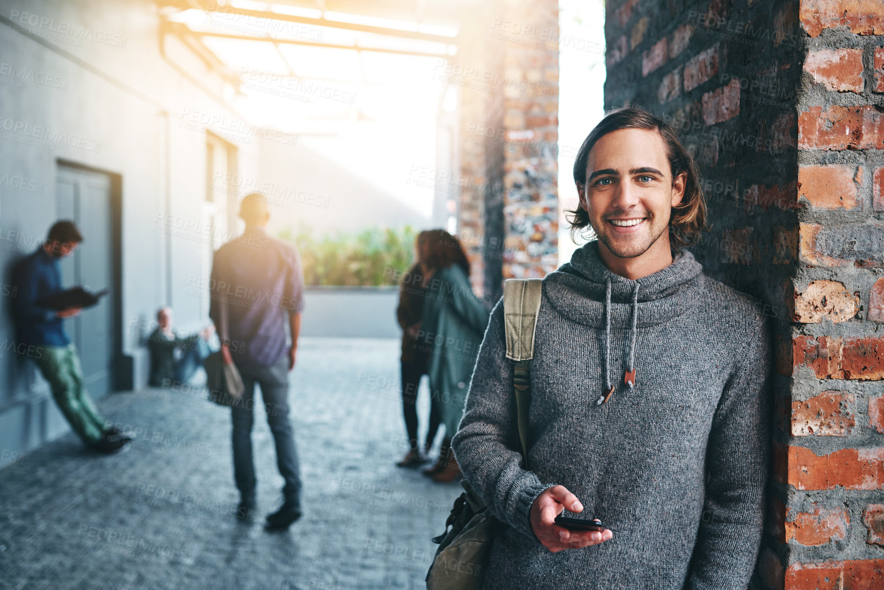 Buy stock photo Shot of a young man using a mobile phone outdoors on campus