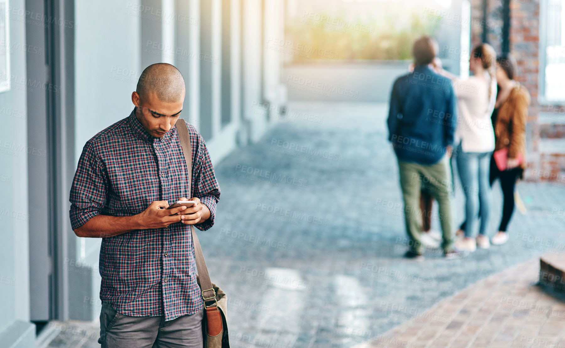 Buy stock photo Shot of a young man using a mobile phone outdoors on campus