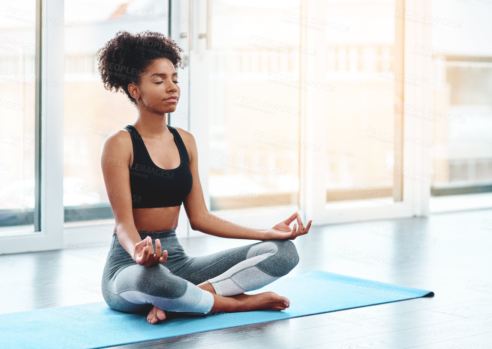 Buy stock photo Shot of a beautiful young woman practising yoga in a studio