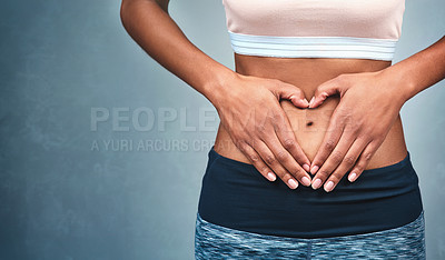 Buy stock photo Heart, fitness and hands of a woman on a stomach isolated on a dark background in studio. Wellness, gut health and a girl with shape for love of body, weight loss and abdomen digestion on backdrop
