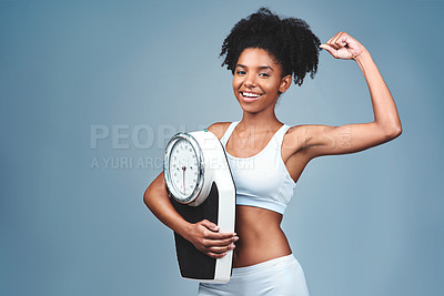 Buy stock photo Black girl, portrait and bicep for scale in studio, weight loss and confident measure on blue background. Female person, fitness and diet for balance, mockup space and strong proud for empowerment