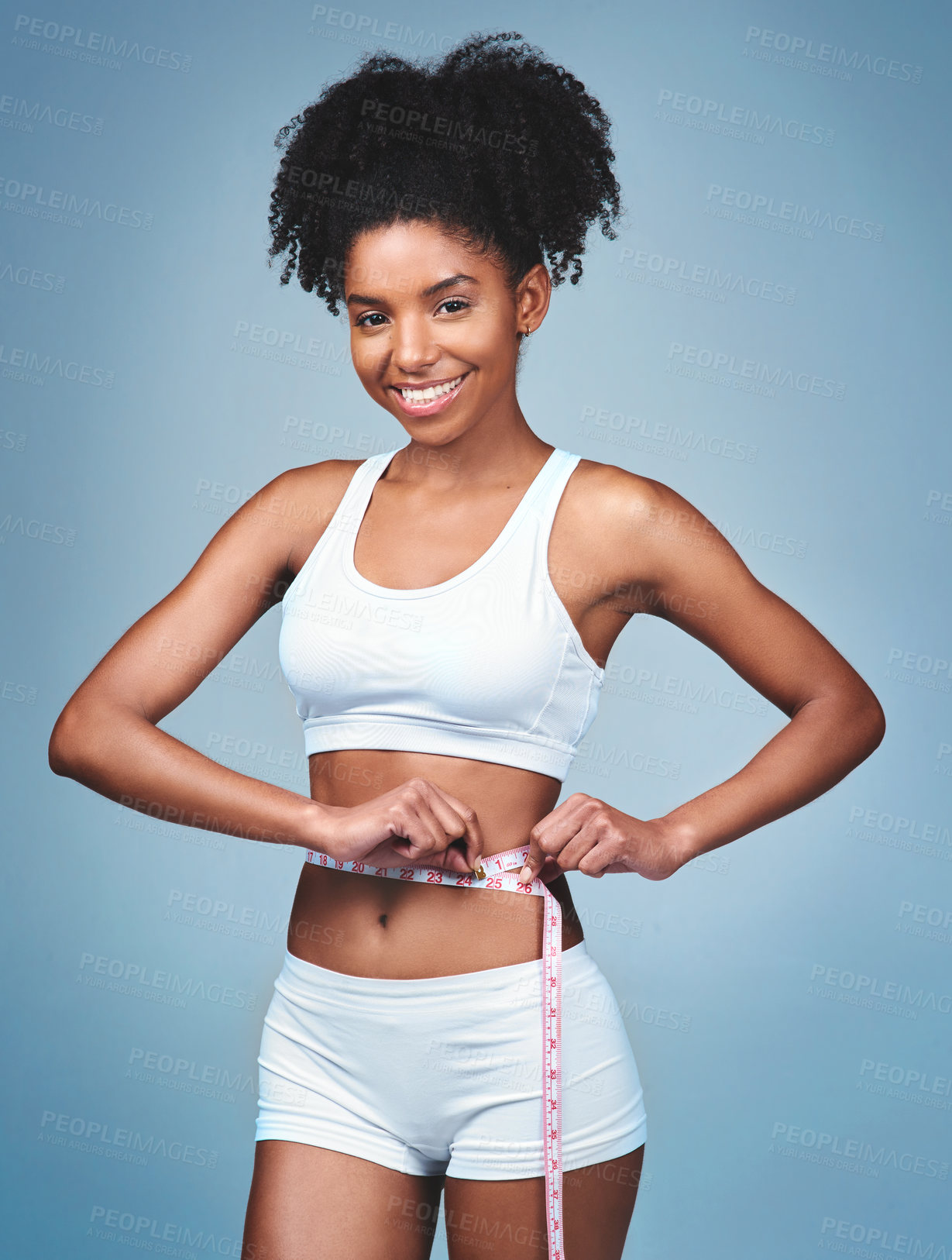 Buy stock photo Shot of an attractive young woman measuring her waist against a grey background