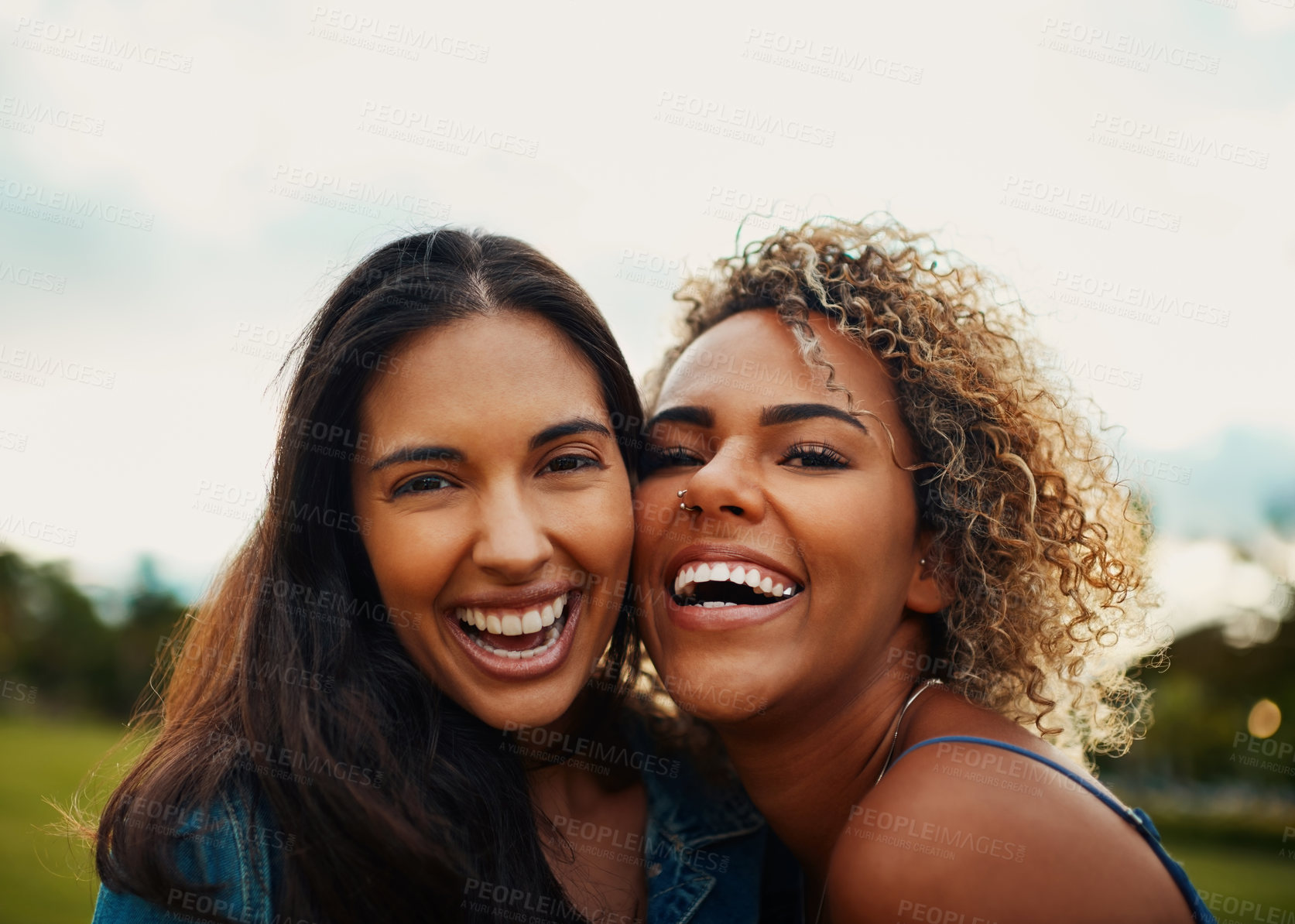 Buy stock photo Cropped portrait of two attractive young girlfriends smiling while standing together in a park