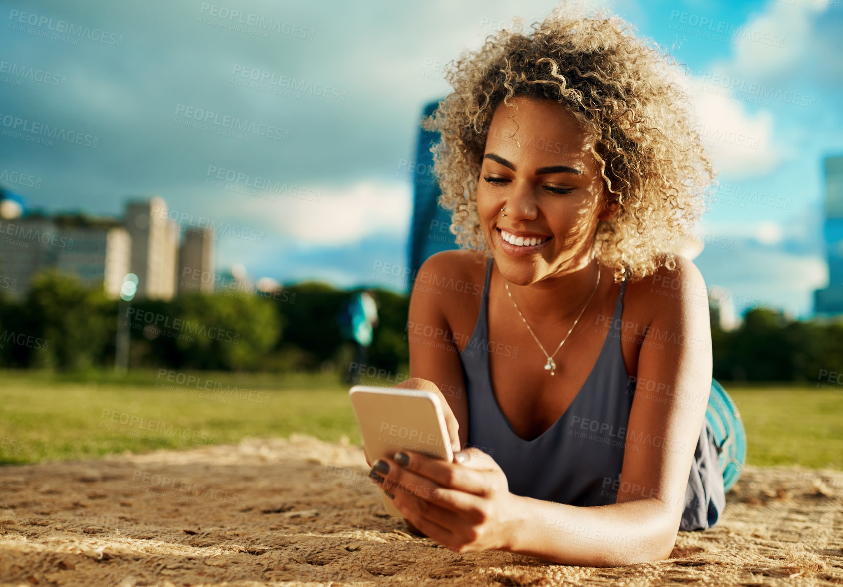 Buy stock photo App, phone and smile with woman at park in city on blanket for communication, social media or wellness. Contact, relax and text message with happy person on grass or lawn for morning or weekend