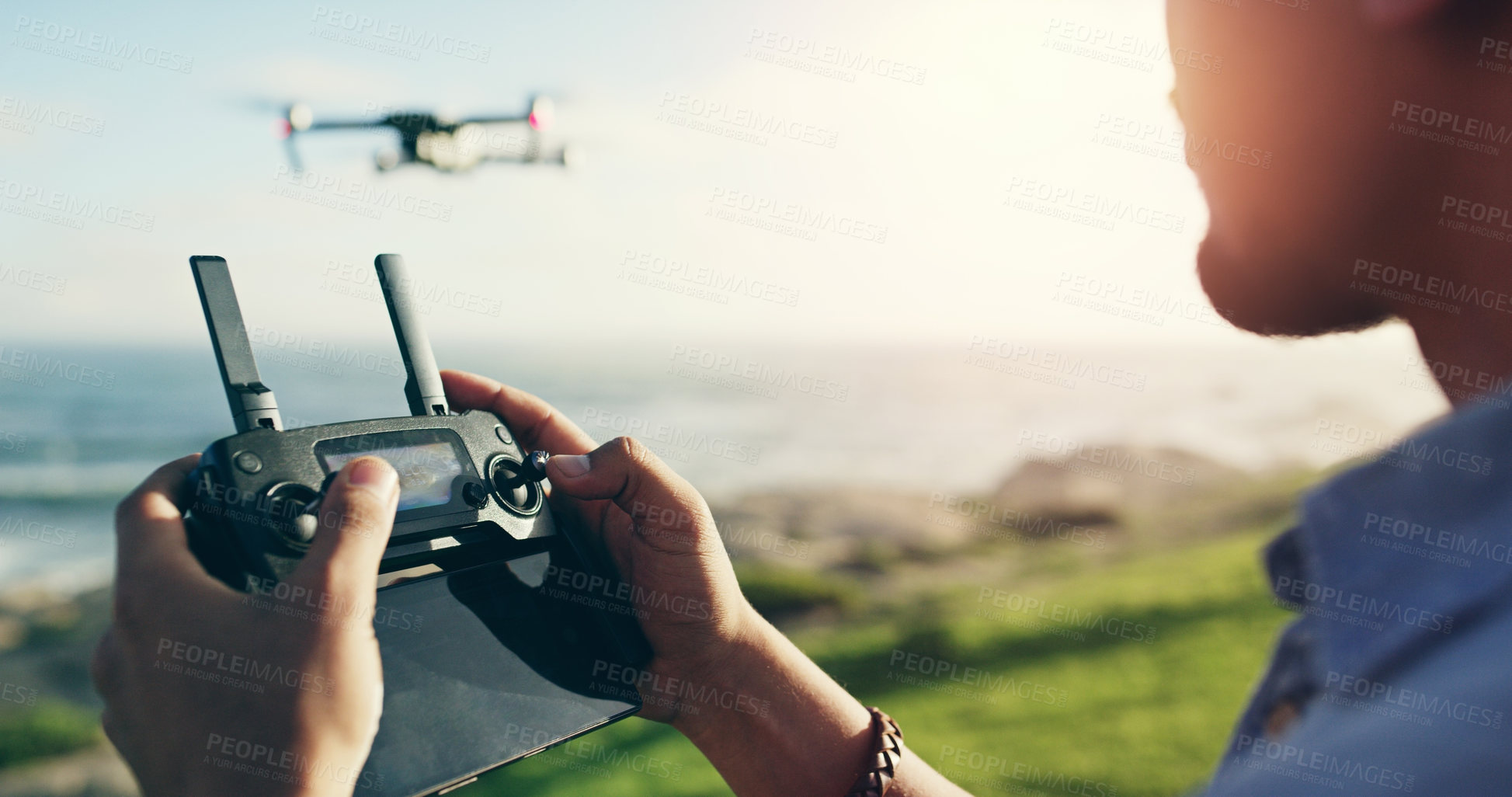 Buy stock photo Shot of an unrecognizable young man flying his drone outdoors