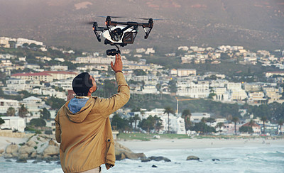 Buy stock photo Shot of a young man flying his drone outdoors