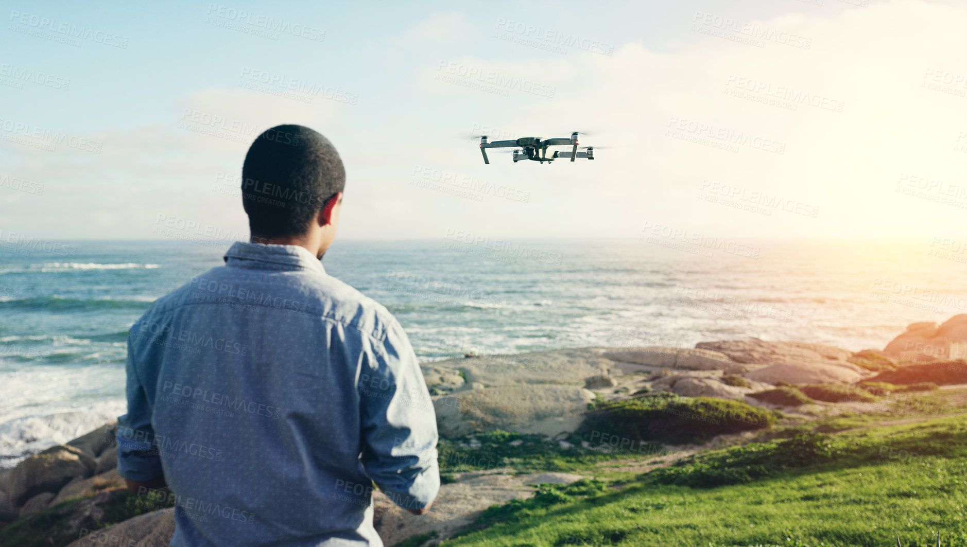 Buy stock photo Rearview shot of a young man flying his drone outdoors