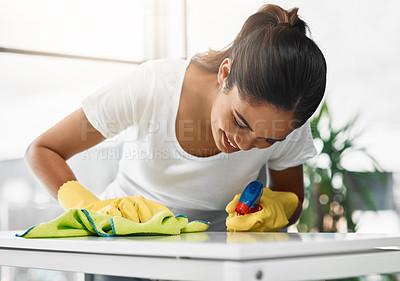 Buy stock photo Cropped shot of an attractive young woman cleaning a table at home