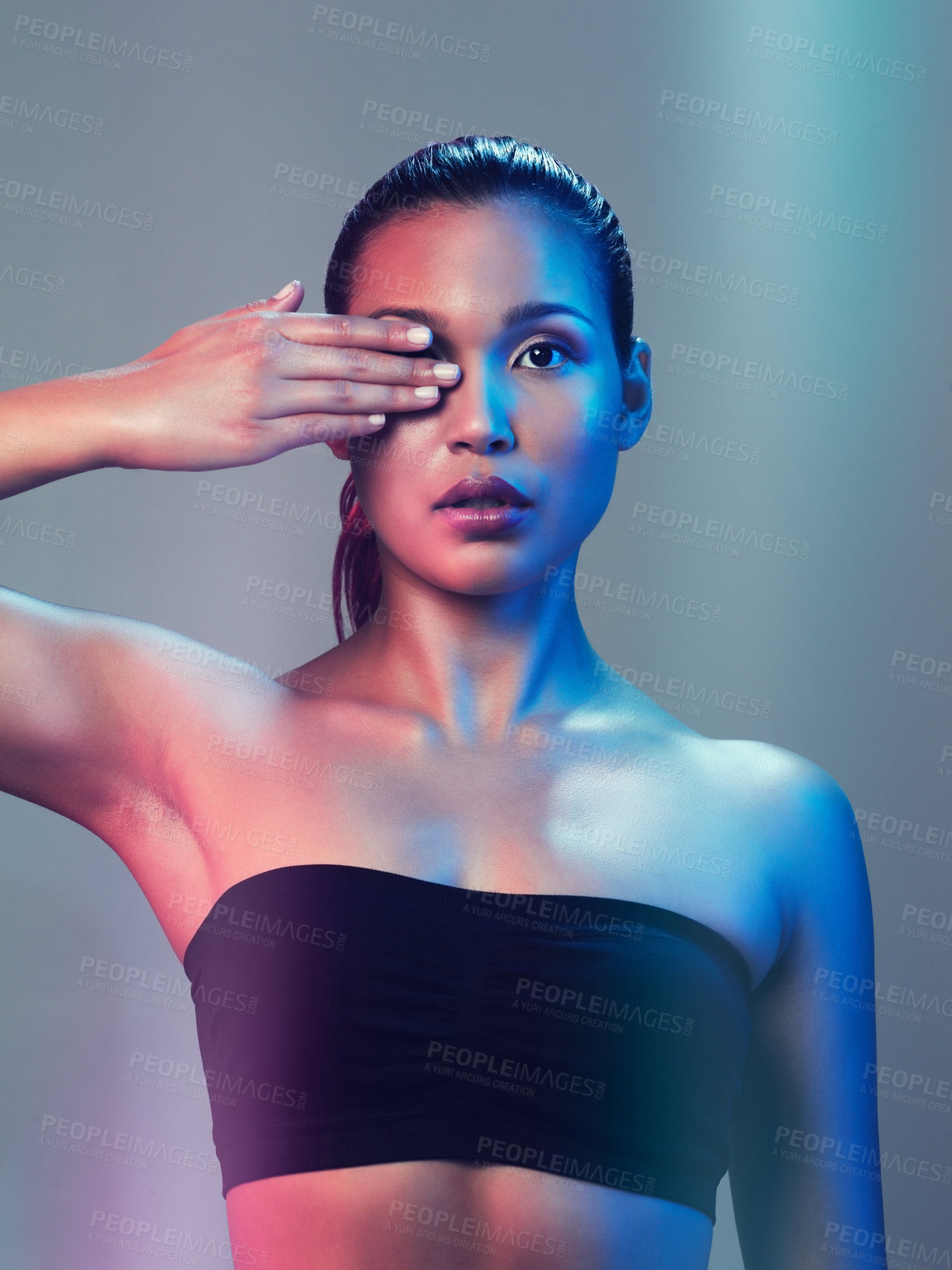Buy stock photo Studio portrait of a beautiful young woman posing while holding her one eye closed against a multi colored background
