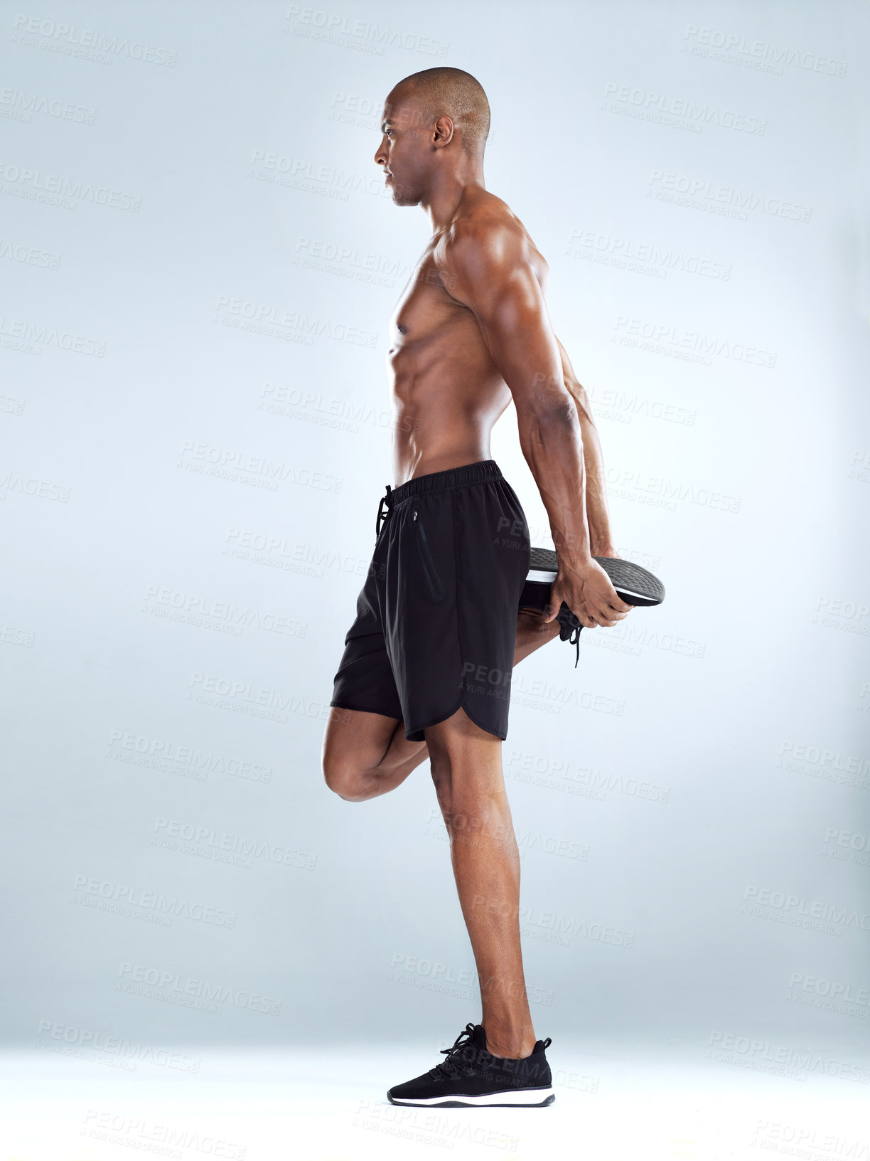 Buy stock photo Studio shot of an athletic young man doing stretching exercises while posing against a grey background