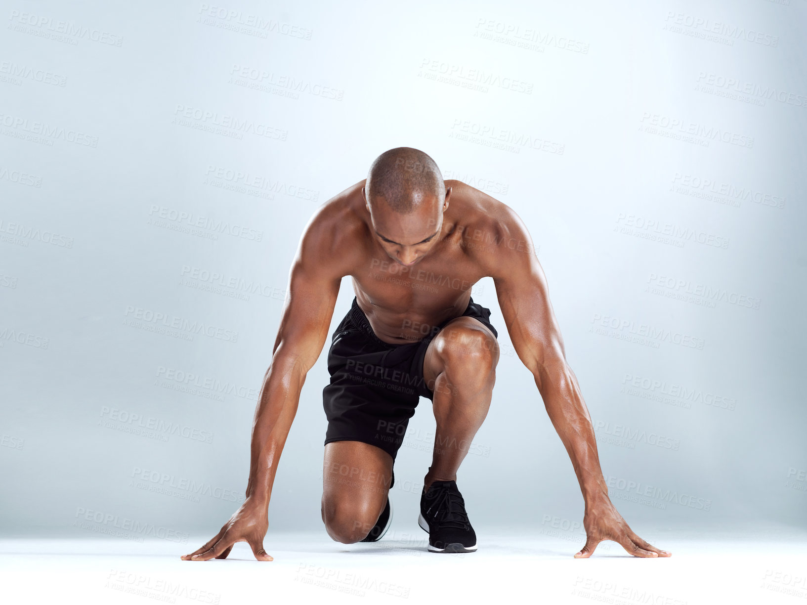 Buy stock photo Studio shot of an athletic young man doing stretching exercises while posing against a grey background