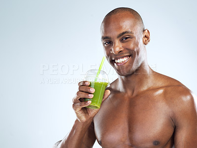 Buy stock photo Studio shot of an athletic young man drinking a healthy smoothy while standing against a grey background