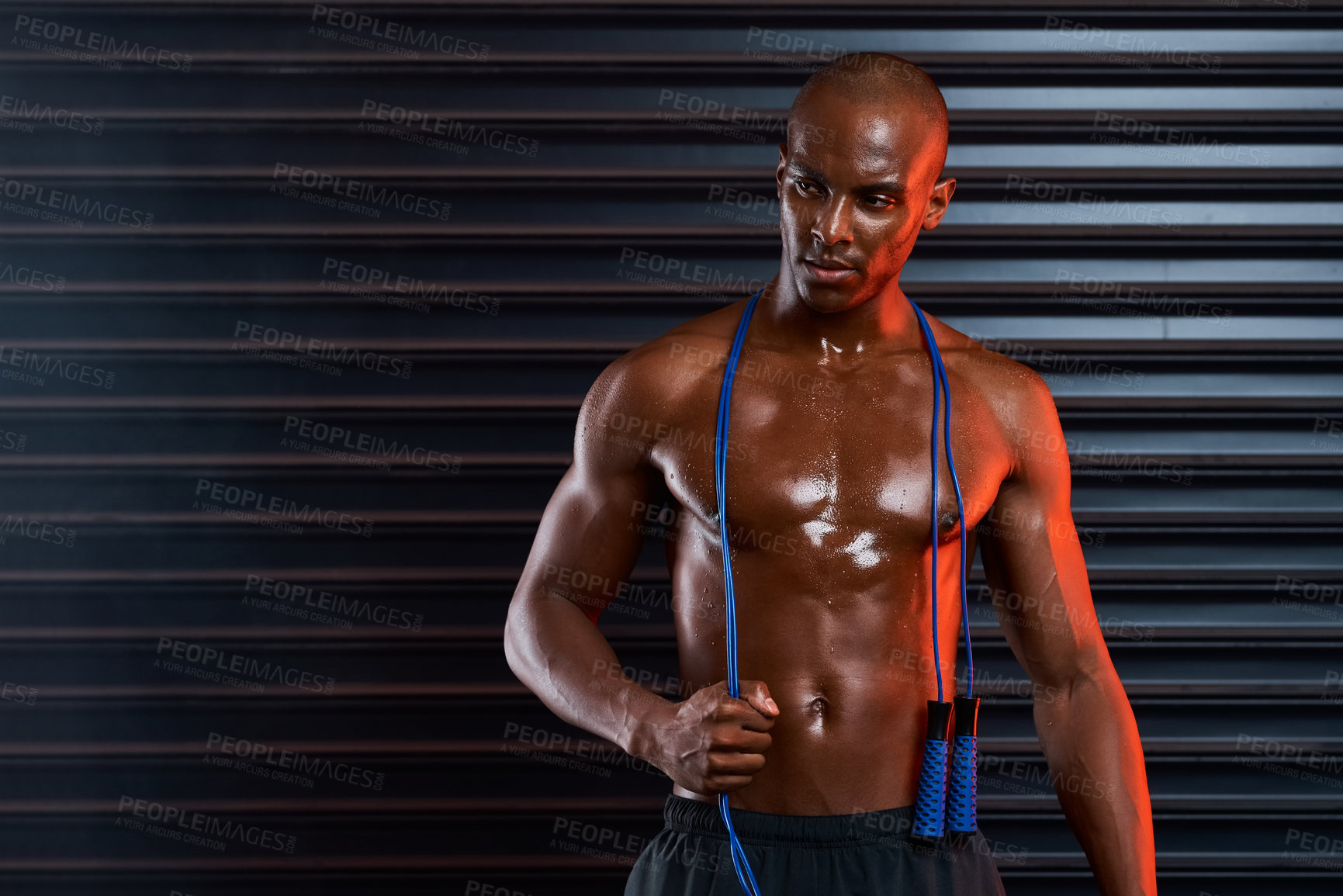 Buy stock photo Studio shot of an athletic young man holding a skipping rope around his shoulders against a grey background