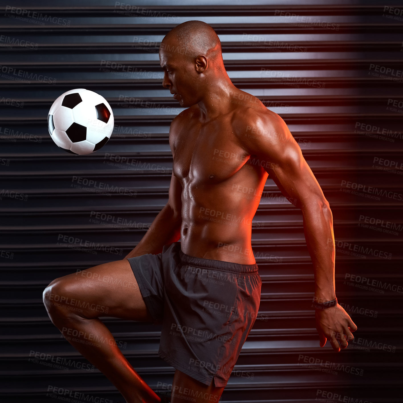 Buy stock photo Studio shot of an athletic young man playing with a soccer ball against a grey background