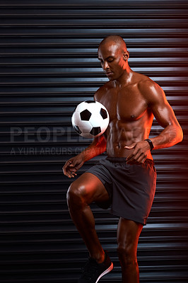 Buy stock photo Studio shot of an athletic young man playing with a soccer ball against a grey background