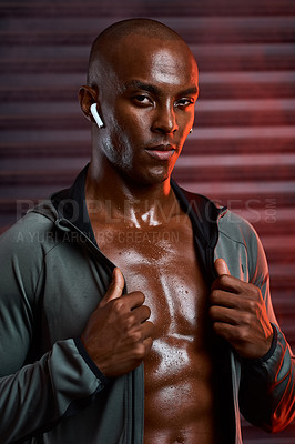 Buy stock photo Studio shot of an athletic young man listening to music on his wireless earphones against a grey background