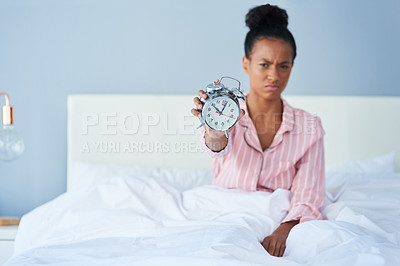 Buy stock photo Shot of an attractive young holding out her alarm clock to the camera in bed at home