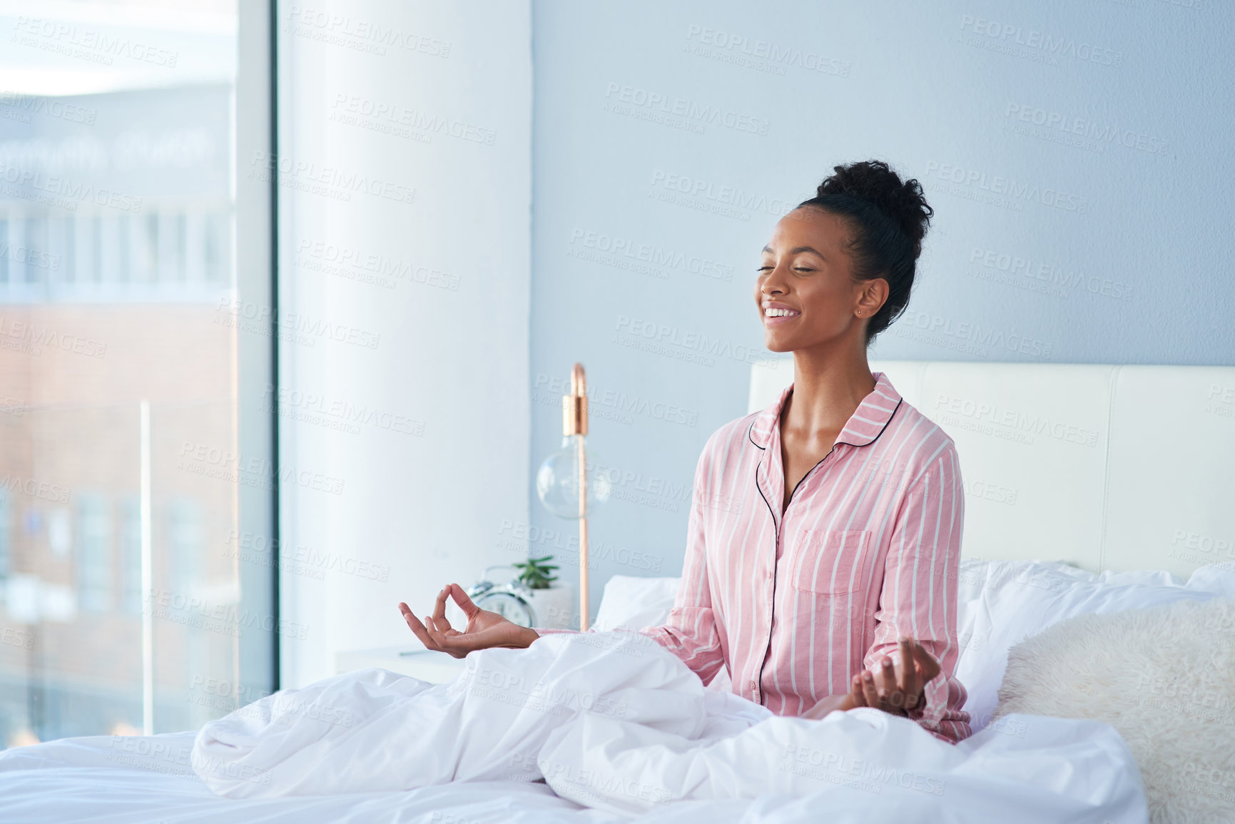 Buy stock photo Shot of an attractive young woman meditating in bed at home