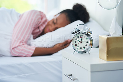 Buy stock photo Shot of an attractive young woman sleeping in bed with her alarm clock on the dresser at home