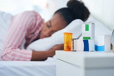 Buy stock photo Shot of an attractive young woman sleeping in bed with her medication on the dresser at home