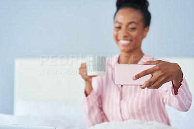 Buy stock photo Shot of an attractive young woman taking a selfie while enjoying her coffee in bed at home