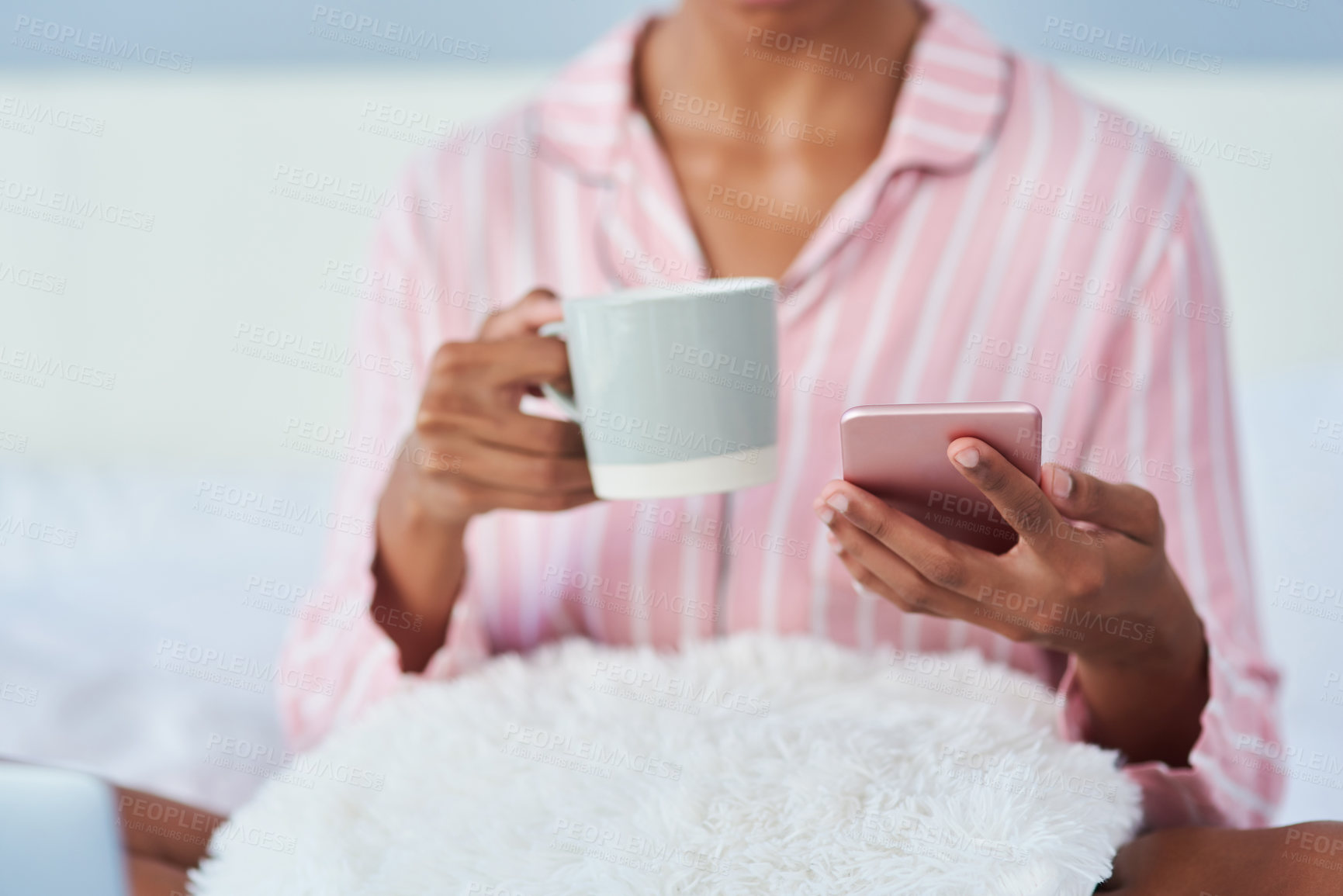 Buy stock photo Shot of an unrecognizable woman drinking coffee and using her cellphone in bed at home