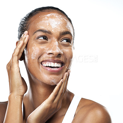 Buy stock photo Studio shot of a beautiful young woman applying skin moisturizer to her face while standing next to a white background