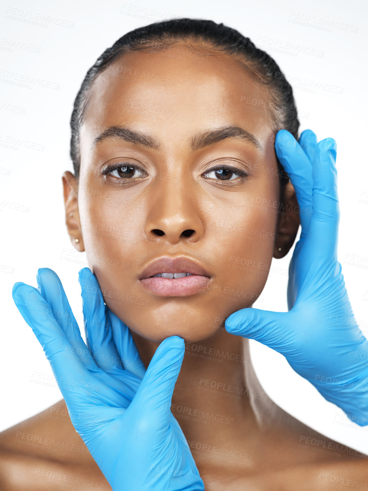 Buy stock photo Studio closeup of an attractive young woman getting her face touched by an unrecognizable person's hands wearing surgical gloves