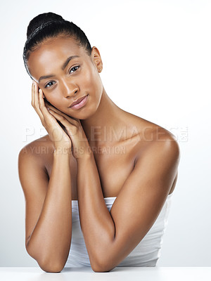 Buy stock photo Studio portrait of an attractive young woman posing and gently touching her face while standing against a white background