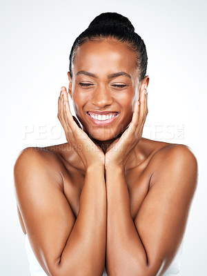 Buy stock photo Studio portrait of an attractive young woman posing and gently touching her face while standing against a white background