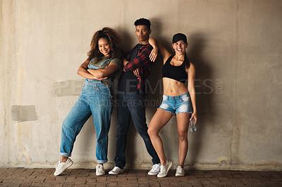 Buy stock photo Portrait of a group of cheerful young friends posing for for a photo while leaning against a wall outside during the day