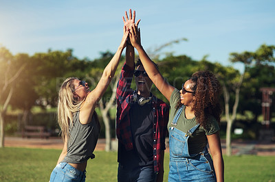 Buy stock photo Shot of a group of cheerful young friends giving each other high fives outside in a park