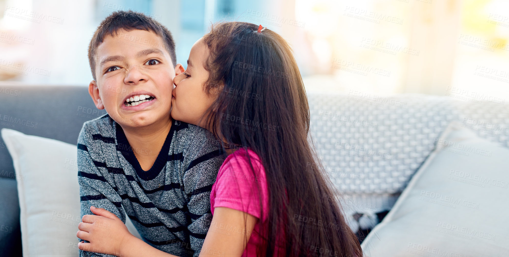 Buy stock photo Shot of an adorable little girl kissing her big brother on the cheek at home
