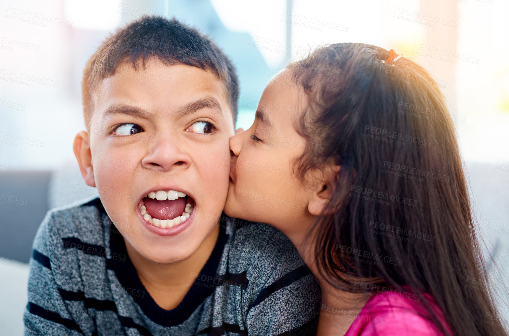 Buy stock photo Young, children and annoyed in kiss on cheek with cute in home as kids in youth. Siblings, expression and irritated as brother and sister on couch in affection, love and childhood development