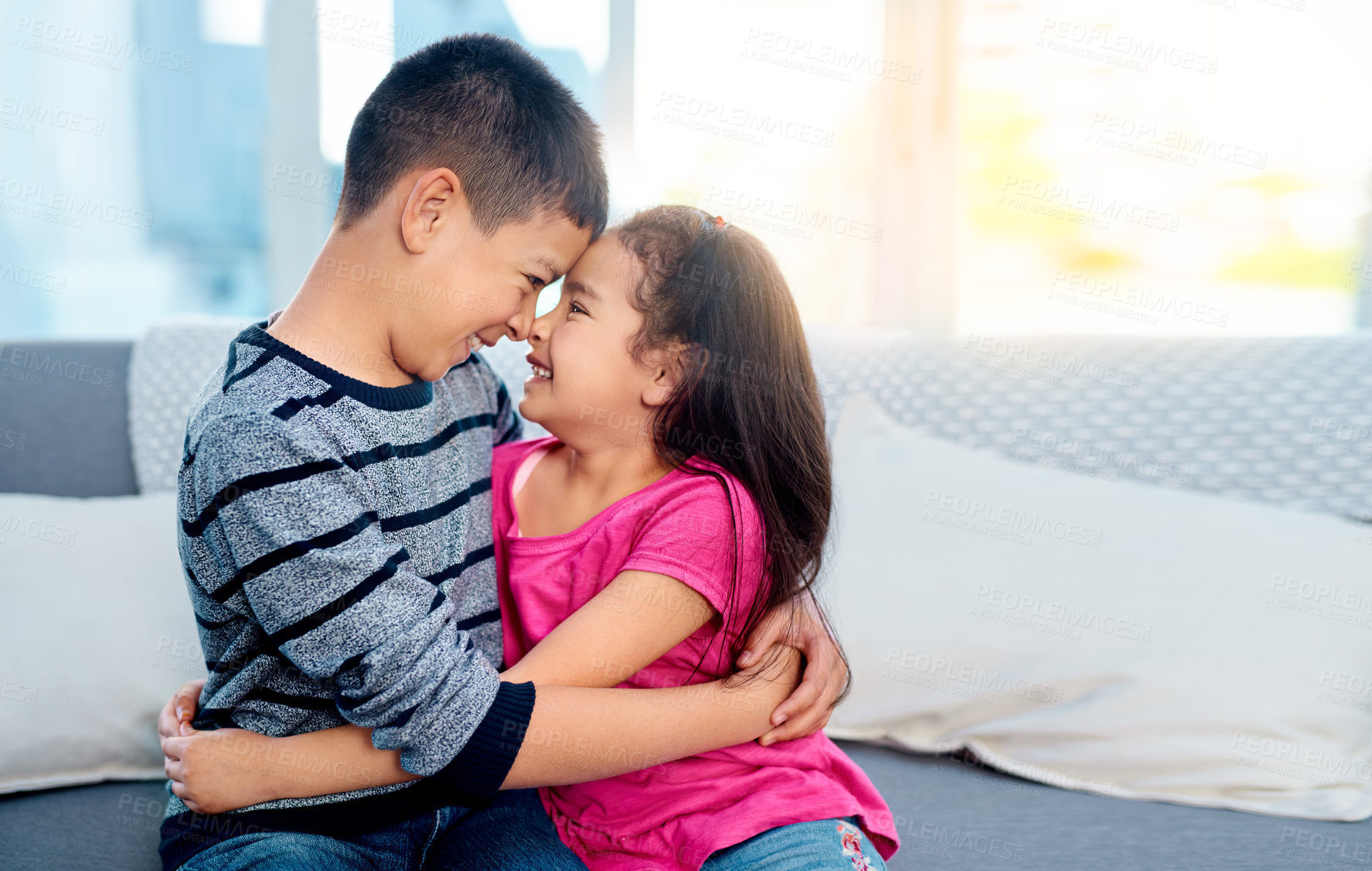 Buy stock photo Young, kids and happy with hugging, smile and joy in family home as children in youth. Siblings, cute and cuddle as brother and sister on couch for affection, love and childhood with noses touching