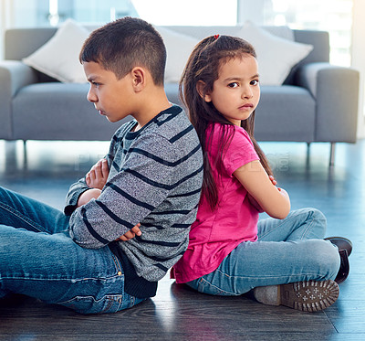 Buy stock photo Shot of two naughty young children sitting down on the floor with their backs facing each other at home